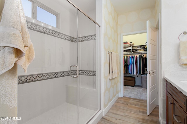 bathroom featuring hardwood / wood-style flooring, a shower with door, and vanity