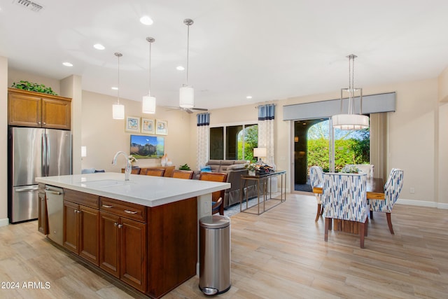 kitchen with appliances with stainless steel finishes, a kitchen island with sink, pendant lighting, and sink