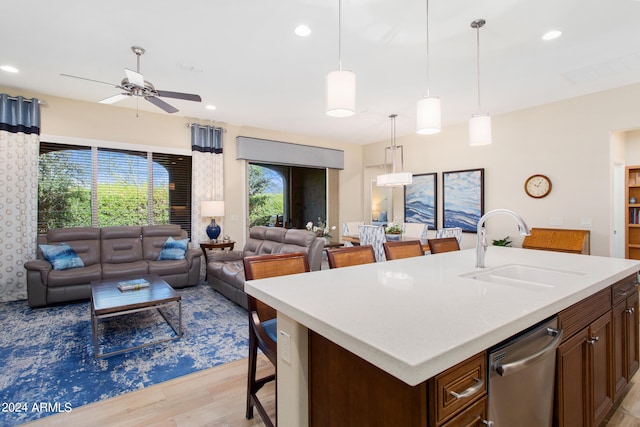 kitchen with a center island with sink, stainless steel dishwasher, sink, and pendant lighting