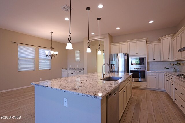 2811 S Jeffry St, Gilbert, AZ 85295 - kitchen featuring appliances with stainless steel finishes, light wood-style flooring, white cabinetry, a kitchen island with sink, and recessed lighting