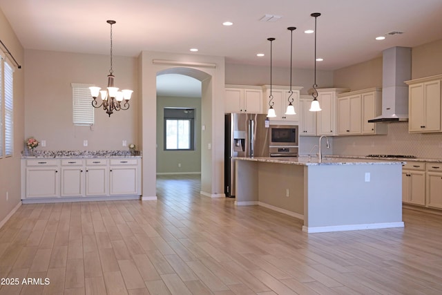 2811 S Jeffry St, Gilbert, AZ 85295 - kitchen with wall chimney range hood, arched walkways, light wood-style floors, appliances with stainless steel finishes, and recessed lighting