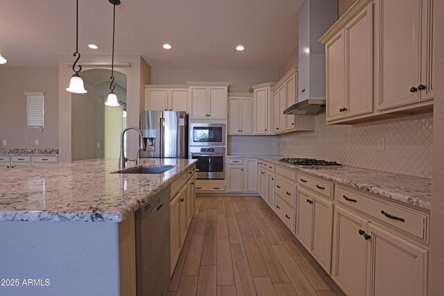 2811 S Jeffry St, Gilbert, AZ 85295 - kitchen featuring appliances with stainless steel finishes, light wood-type flooring, wall chimney exhaust hood, tasteful backsplash, and light stone countertops