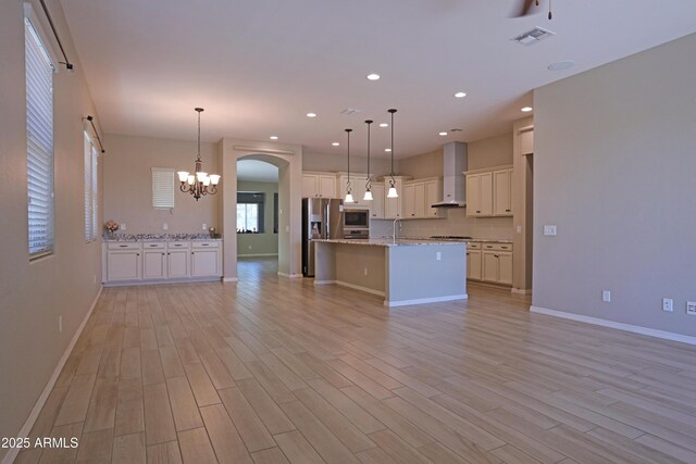 2811 S Jeffry St, Gilbert, AZ 85295 - kitchen featuring wall chimney exhaust hood, open floor plan, stainless steel fridge with ice dispenser, a chandelier, and light wood-style flooring
