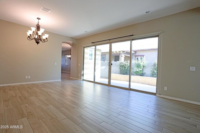 2811 S Jeffry St, Gilbert, AZ 85295 - empty room featuring a chandelier, arched walkways, and light wood finished floors