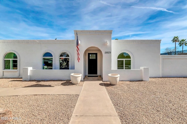 mediterranean / spanish-style house with a fenced front yard and stucco siding