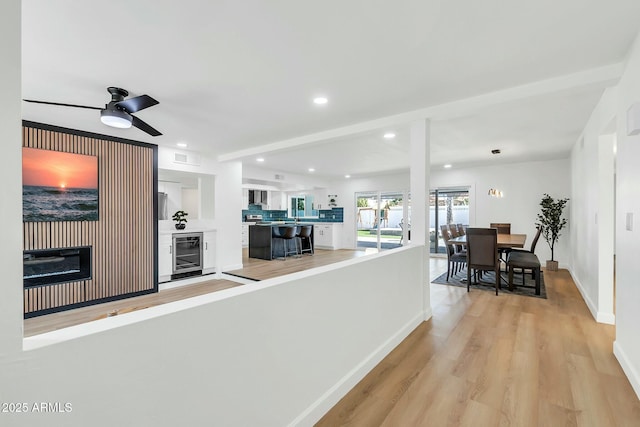 kitchen with beverage cooler, white cabinets, light wood-style flooring, and recessed lighting