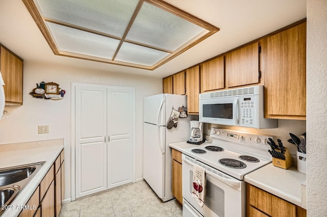 kitchen with light tile patterned flooring, white appliances, and sink