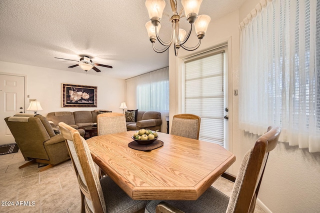 dining space featuring a textured ceiling and ceiling fan with notable chandelier