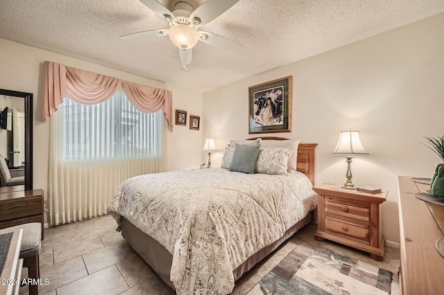 bedroom with tile patterned flooring, ceiling fan, and a textured ceiling