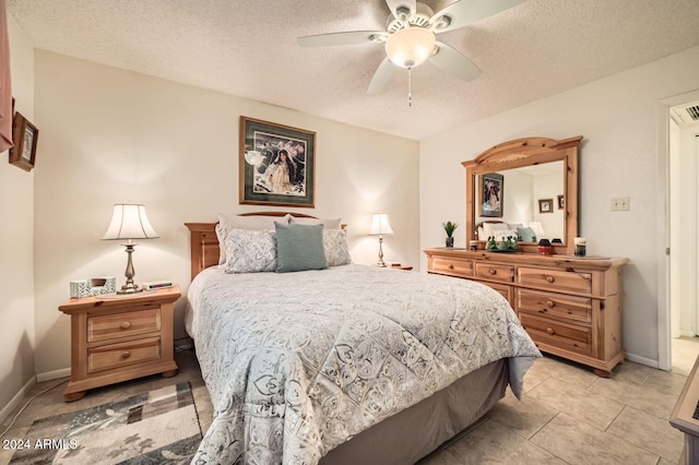 tiled bedroom with ceiling fan and a textured ceiling