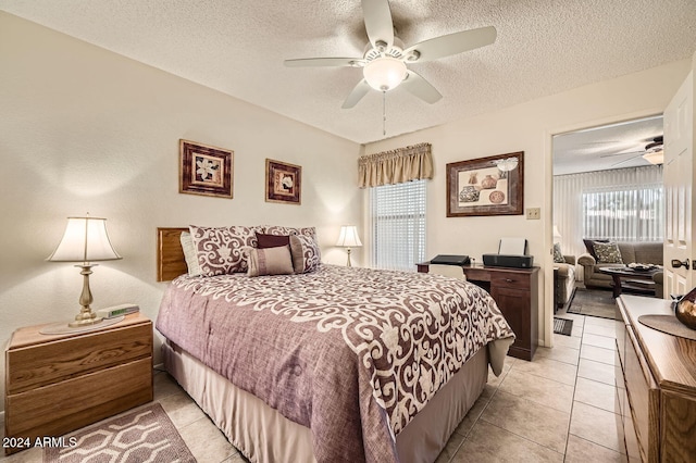 bedroom with ceiling fan, light tile patterned flooring, and a textured ceiling