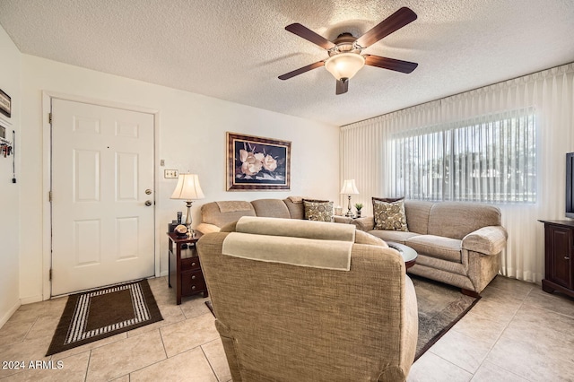 living room with a textured ceiling, ceiling fan, and light tile patterned flooring