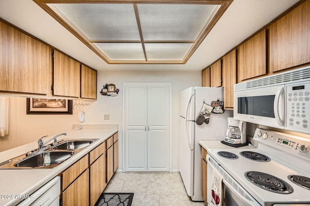 kitchen featuring light tile patterned floors, white appliances, and sink