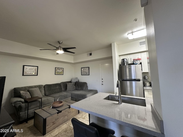 living room with visible vents and a ceiling fan