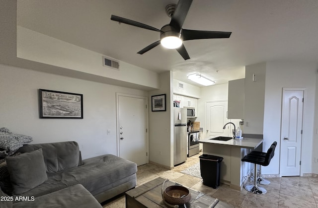 living area featuring visible vents, baseboards, and a ceiling fan