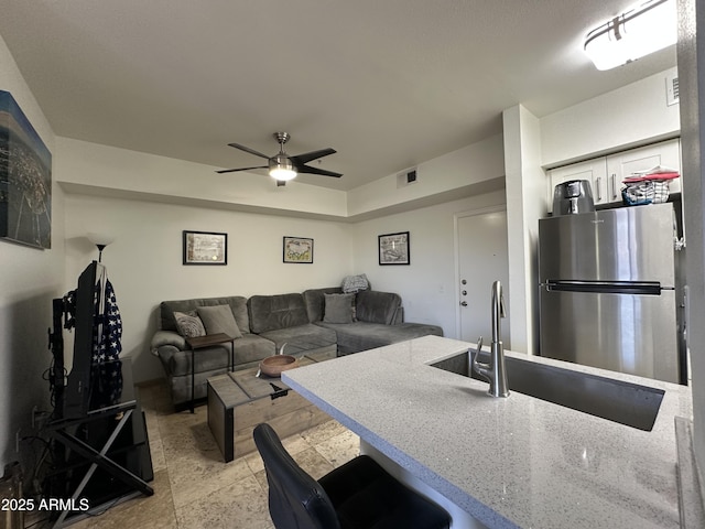 living area with visible vents and a ceiling fan