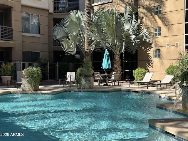 community pool with a patio area and fence