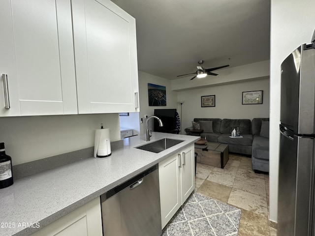 kitchen with a sink, stone finish flooring, appliances with stainless steel finishes, and white cabinets