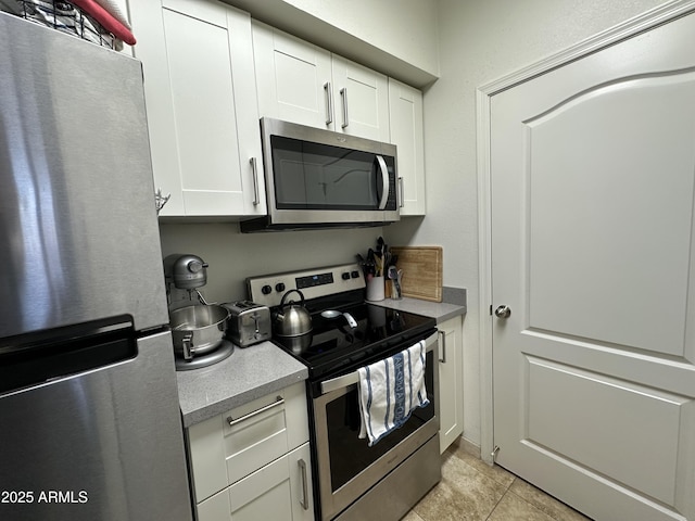 kitchen with light tile patterned floors, stainless steel appliances, white cabinets, and light countertops