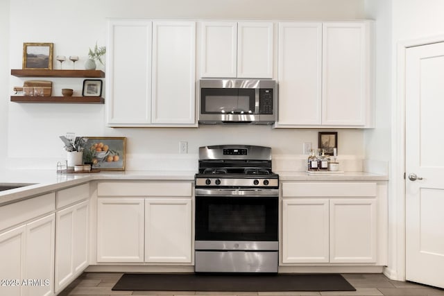 kitchen with open shelves, stainless steel appliances, and white cabinetry