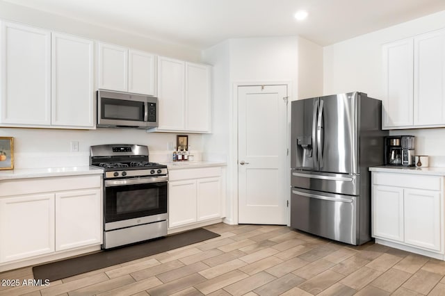 kitchen with wood finish floors, white cabinetry, recessed lighting, appliances with stainless steel finishes, and light countertops