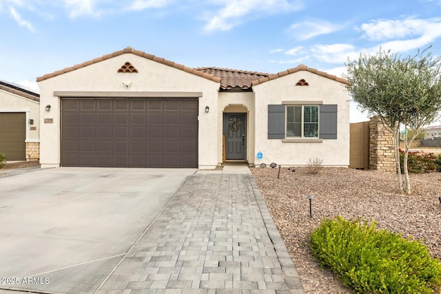 mediterranean / spanish house featuring a tile roof, an attached garage, driveway, and stucco siding