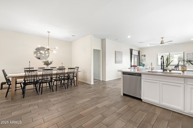 kitchen with dishwasher, white cabinetry, wood tiled floor, and a sink