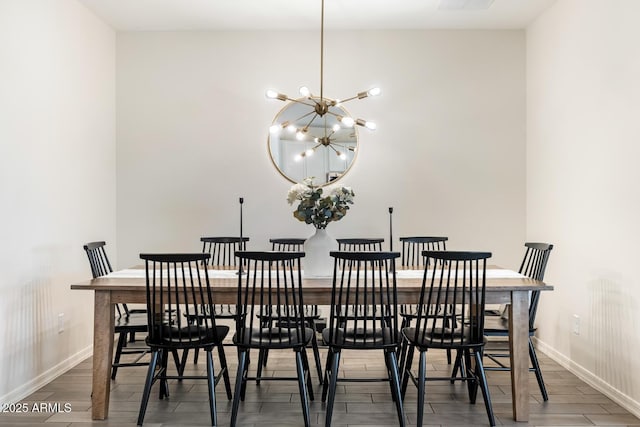 dining room featuring a chandelier, baseboards, and wood finished floors