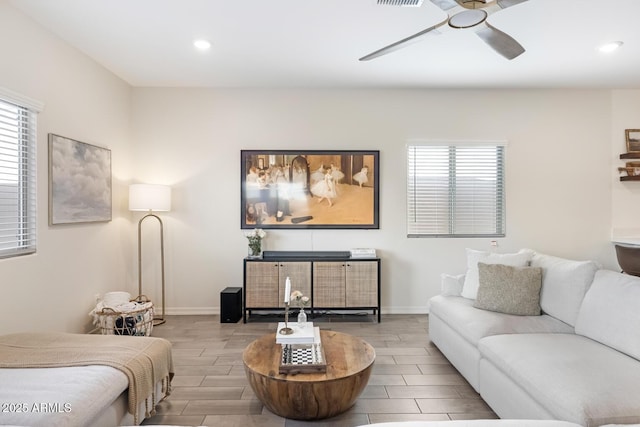 living area with a wealth of natural light, baseboards, a ceiling fan, and wood tiled floor