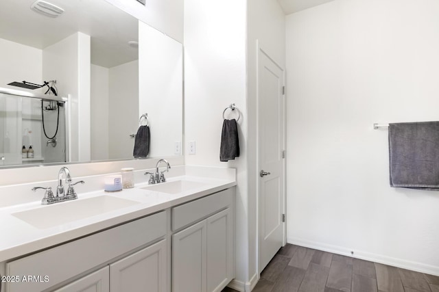 bathroom featuring a sink, visible vents, wood finished floors, and double vanity