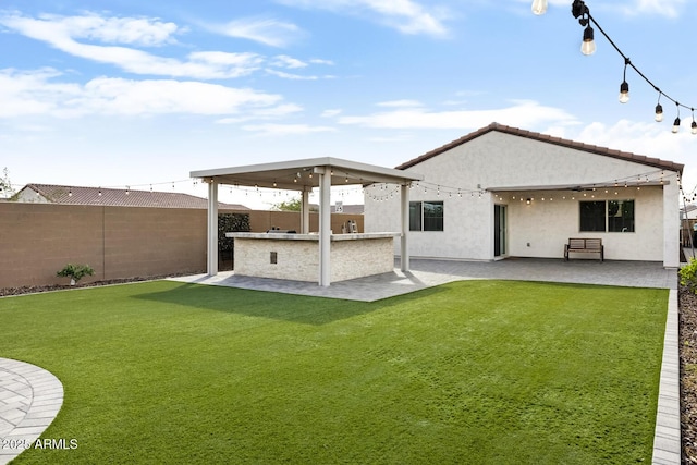 rear view of property with stucco siding, a lawn, a fenced backyard, area for grilling, and a patio