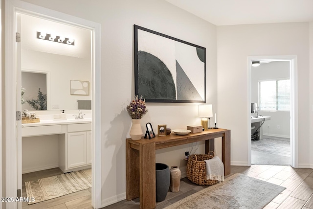 hall featuring light wood-type flooring, baseboards, and a sink