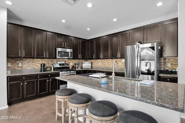3436 E Gary Way, Gilbert, AZ 85234 - kitchen featuring stainless steel appliances, a kitchen bar, dark stone counters, and recessed lighting
