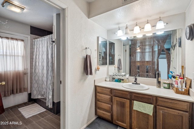 full bathroom featuring a textured wall, vanity, curtained shower, a textured ceiling, and baseboards