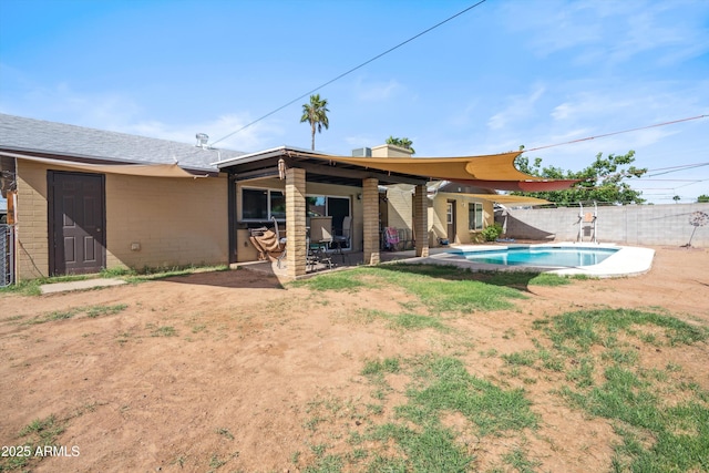 rear view of property with a fenced backyard, a patio, and concrete block siding