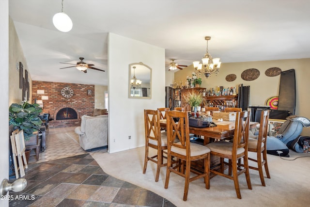 dining area with a chandelier, a ceiling fan, a brick fireplace, and baseboards