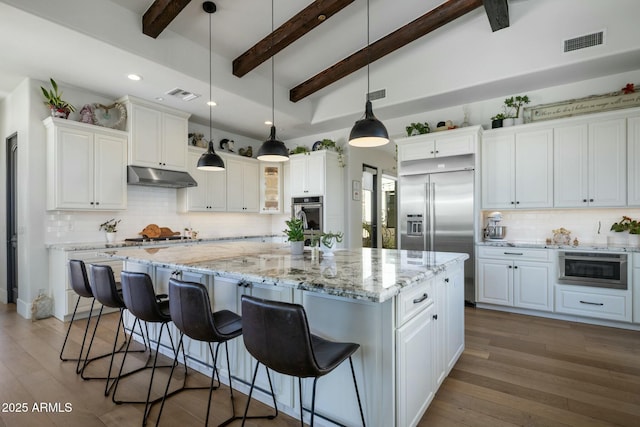 kitchen featuring under cabinet range hood, visible vents, a kitchen island, and appliances with stainless steel finishes