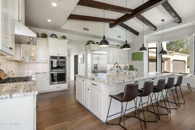 kitchen with range hood, visible vents, lofted ceiling with beams, appliances with stainless steel finishes, and dark wood finished floors