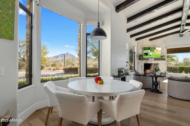 dining area featuring a mountain view, baseboards, vaulted ceiling with beams, and wood finished floors