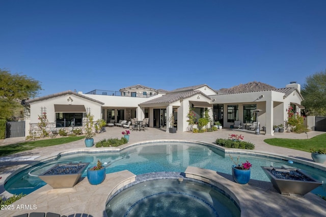 back of house with a patio, a fire pit, stucco siding, and a pool with connected hot tub