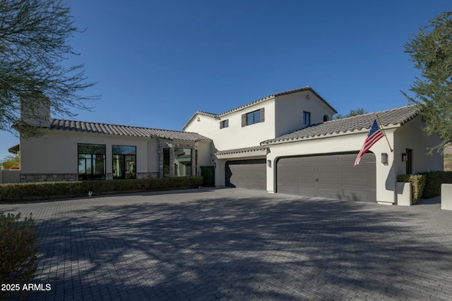 mediterranean / spanish-style house with a tiled roof, an attached garage, a chimney, stucco siding, and driveway