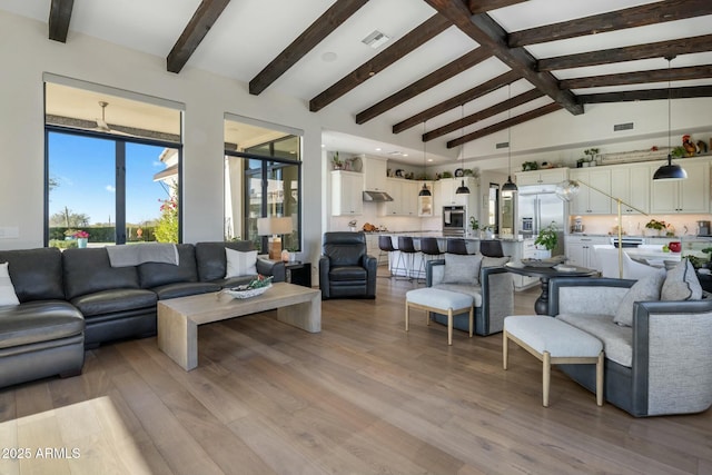 living room featuring beam ceiling, high vaulted ceiling, and light wood-style floors