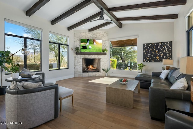 living room with a fireplace, ceiling fan, hardwood / wood-style flooring, and lofted ceiling with beams