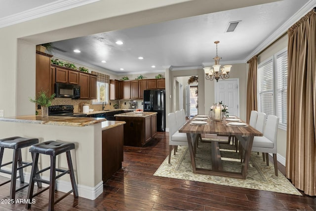 kitchen featuring pendant lighting, dark wood-type flooring, black appliances, kitchen peninsula, and a chandelier