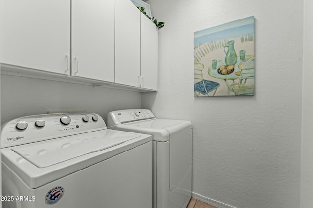 clothes washing area with washing machine and dryer and cabinets