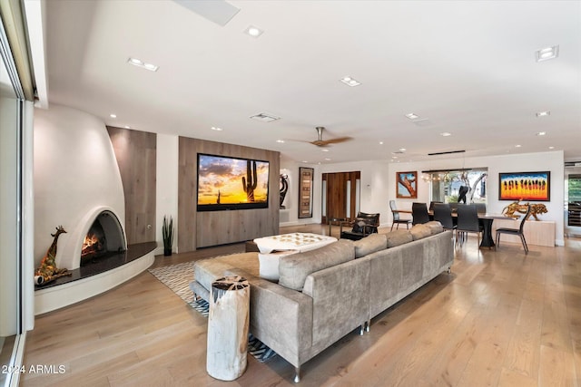 living room with ceiling fan, a fireplace, and light hardwood / wood-style floors