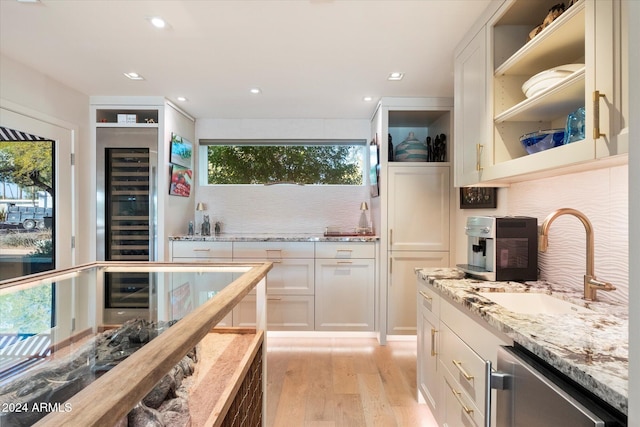 kitchen featuring dishwasher, sink, light hardwood / wood-style flooring, backsplash, and white cabinets