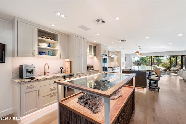 kitchen with white cabinetry, light hardwood / wood-style flooring, a kitchen island, and decorative light fixtures