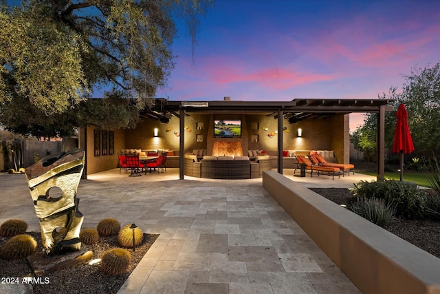 back house at dusk with an outdoor living space with a fireplace and a patio