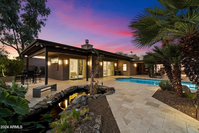 pool at dusk featuring central air condition unit and a patio area